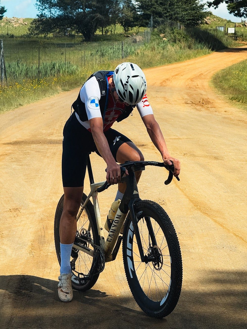 A gravel racer bent over the handlebars on a dirt road, emptied after an effort